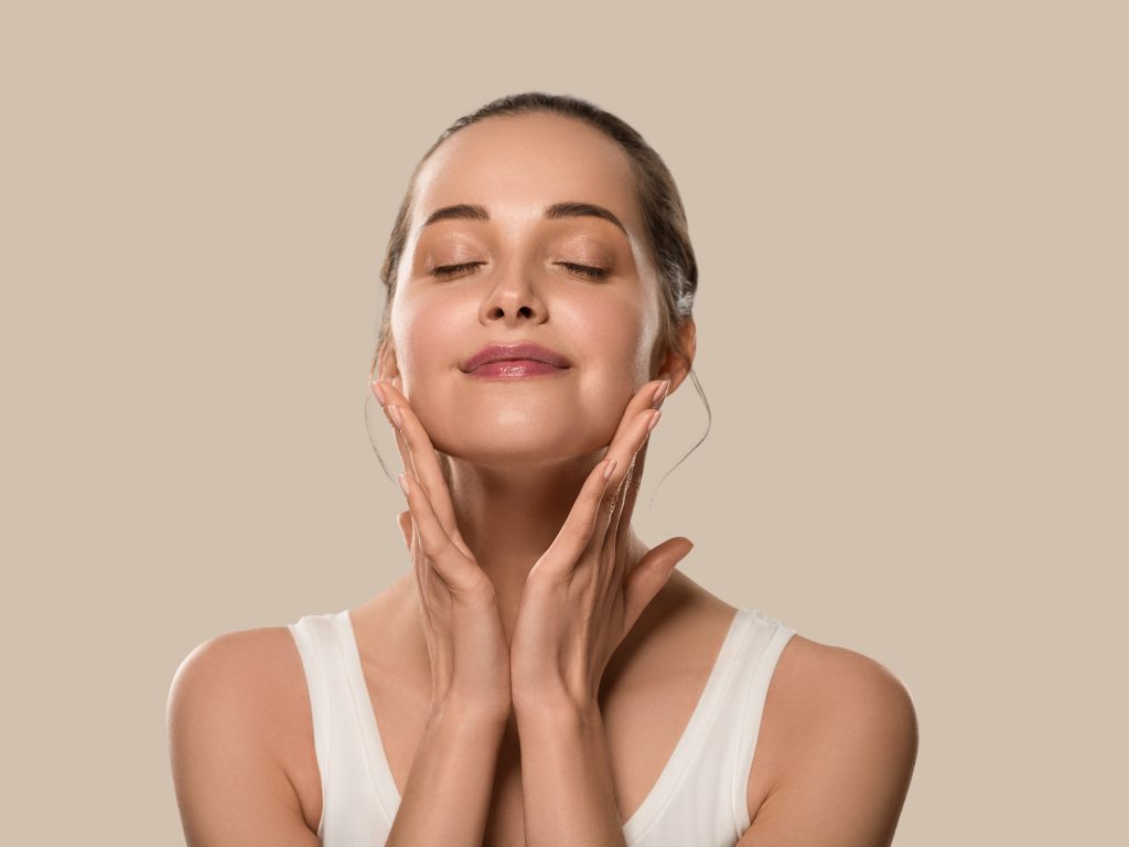 Mujer joven feliz y relajada satisfecha con la piel de su rostro después de recibir un tratamiento facial de peeling en nuestra clínica estética de Sevilla